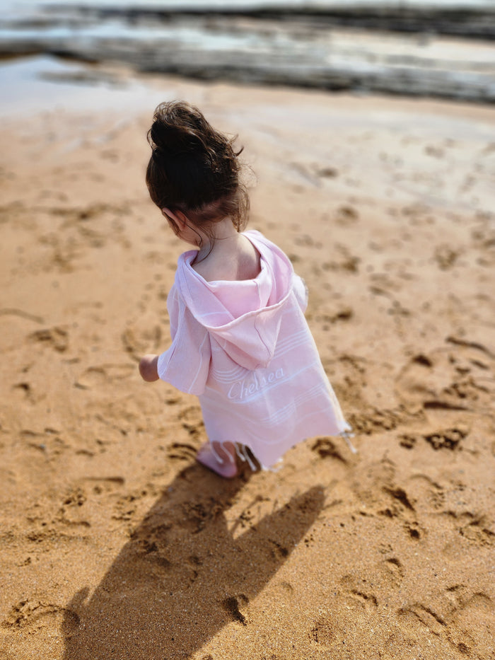 Personalised kids poncho towel featuring a child’s name in elegant script, ideal for making a unique gift. Beach side location